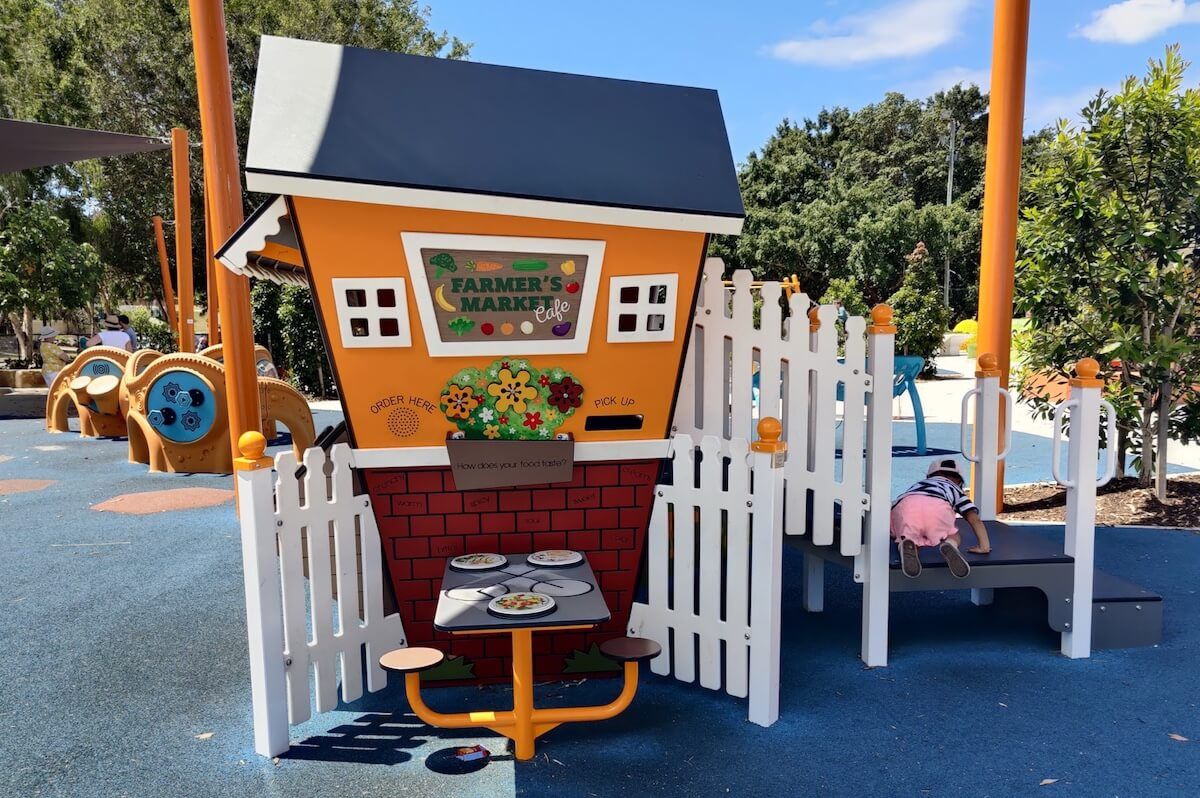 Fun farmer’s market cubby house with sensory play elements at the Hills District All Abilities Playground in Brisbane.